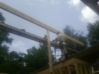 Carpenter setting a ridge beam over a new addition frame — Ice Dam Removal by Roofing Brothers in Ludlow