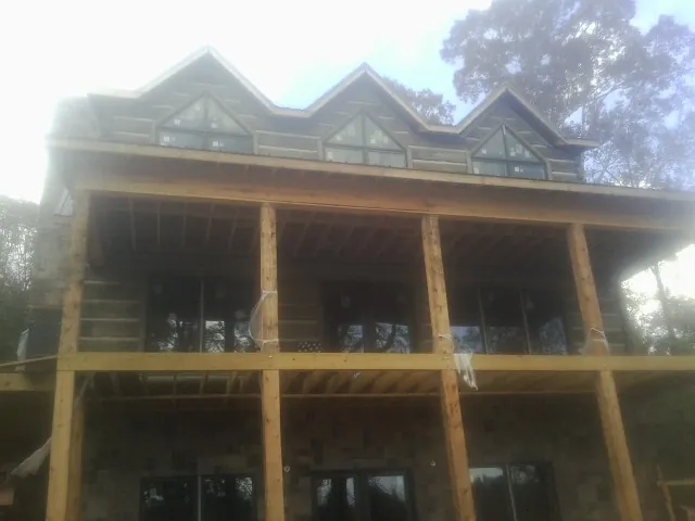 Dormers and porch framing on a large log home under construction — Roof Coating work by our crew in Ludlow