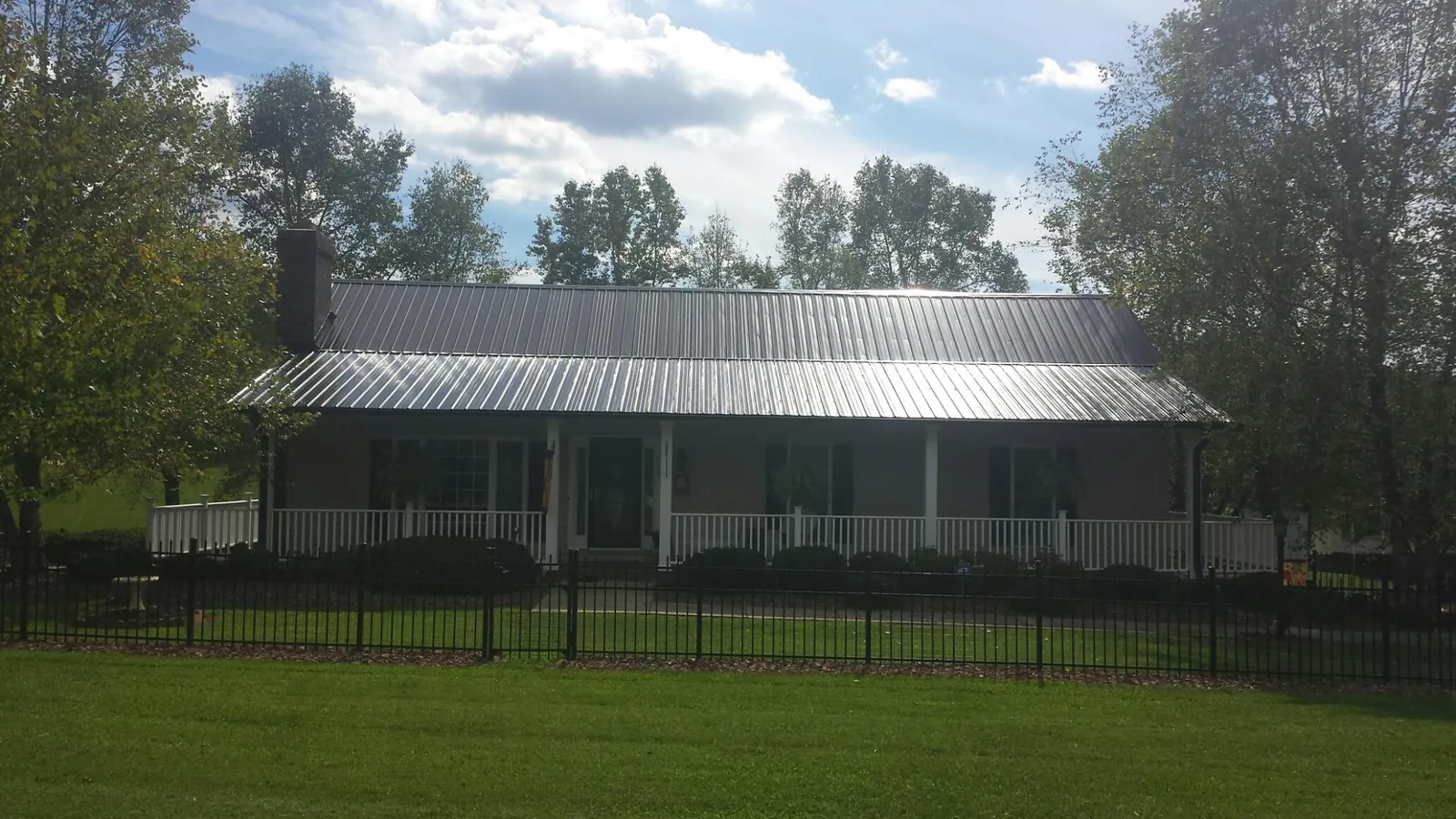 Gray metal roof on a brick ranch with a full width front porch — Gutter Guard Installation work by our crew in Ludlow