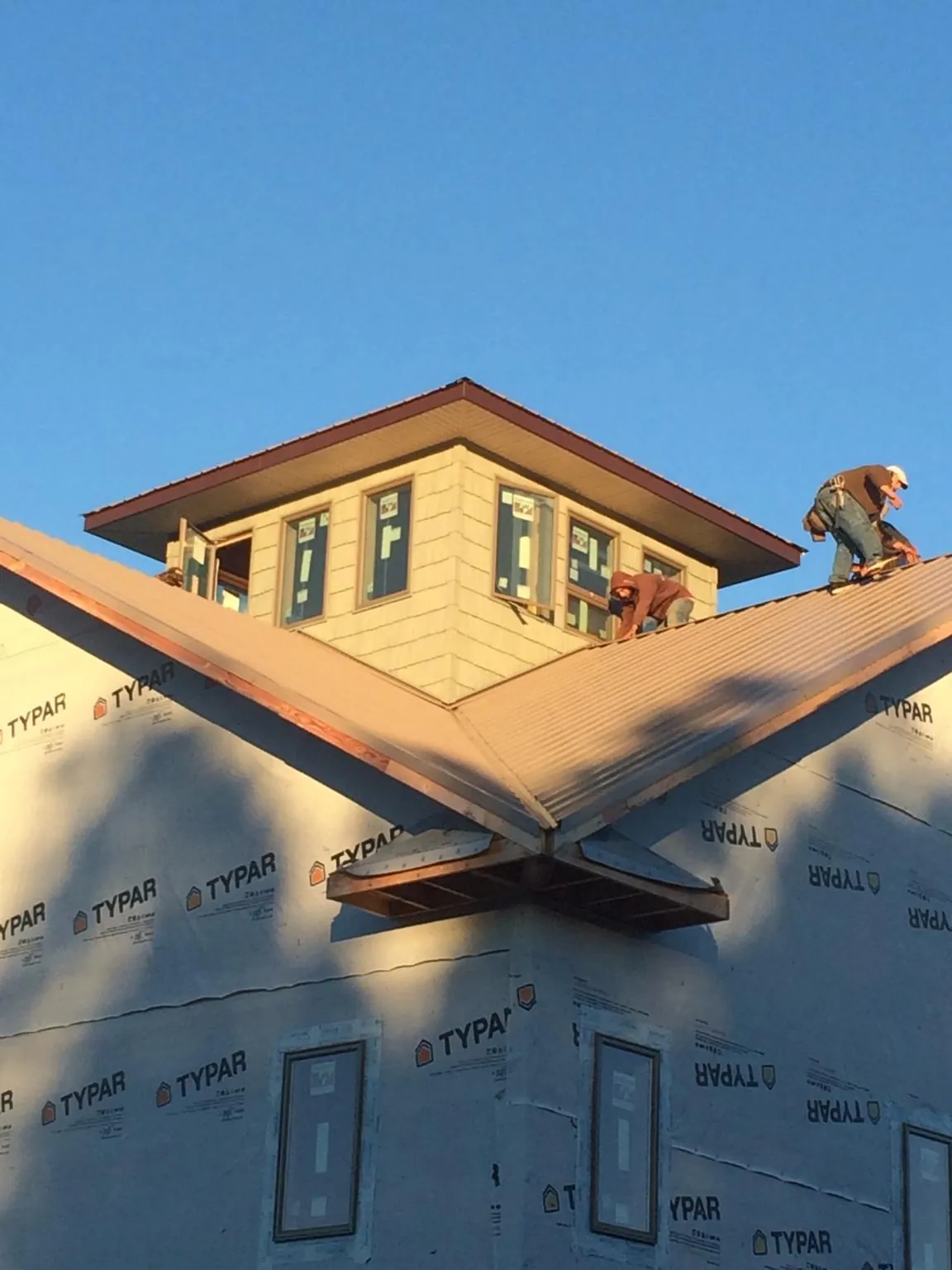 Roofers working around a rooftop cupola on a new metal roof at sunset — Roof Waterproofing in Ludlow by Roofing Brothers